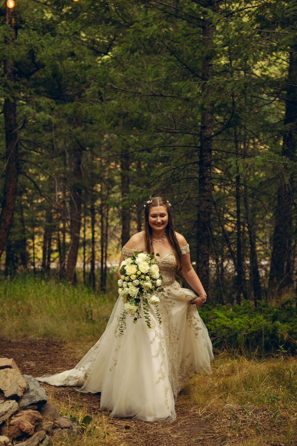 Bridge walks through trees Summer storm wedding at Juniper Lodge & Treehouses in Evergreen, Colorado during her summer wedding.