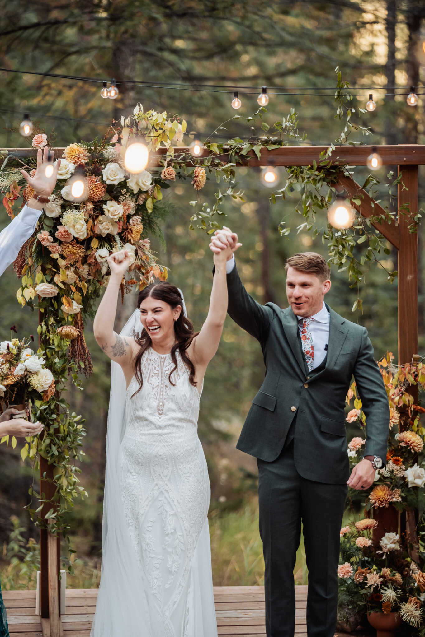 Wedding ceremony under wooden arch with Snowberry Floral arrangements at Juniper Lodge & Treehouses