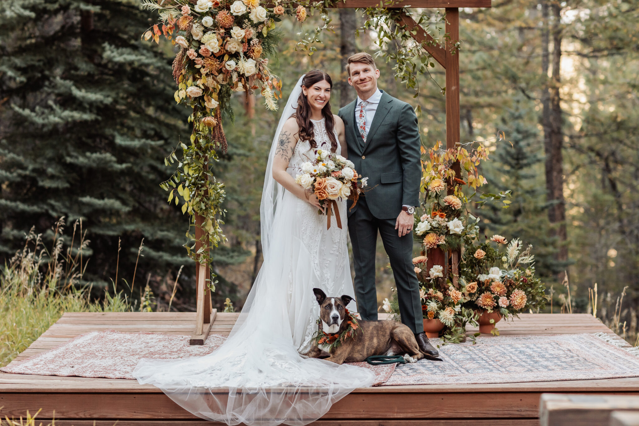 Wedding ceremony under wooden arch with Snowberry Floral arrangements at Juniper Lodge & Treehouses