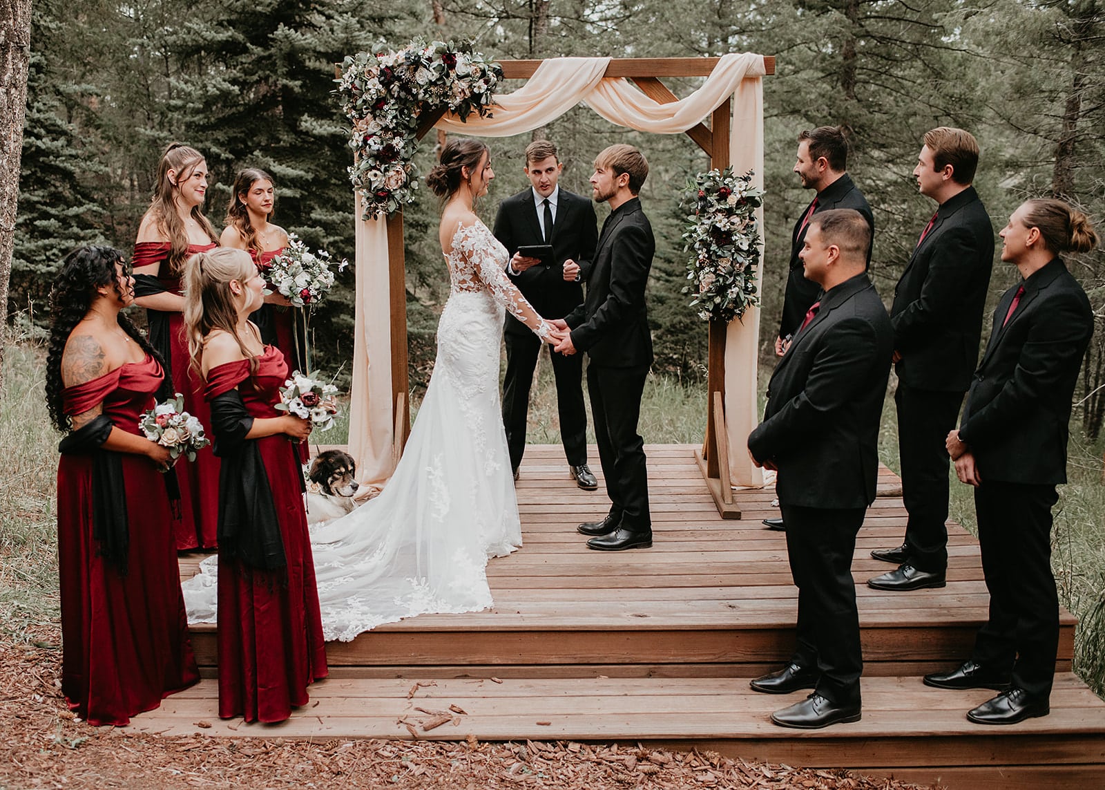 Ceremony in the meadow with string quartet and burgundy floral arch.