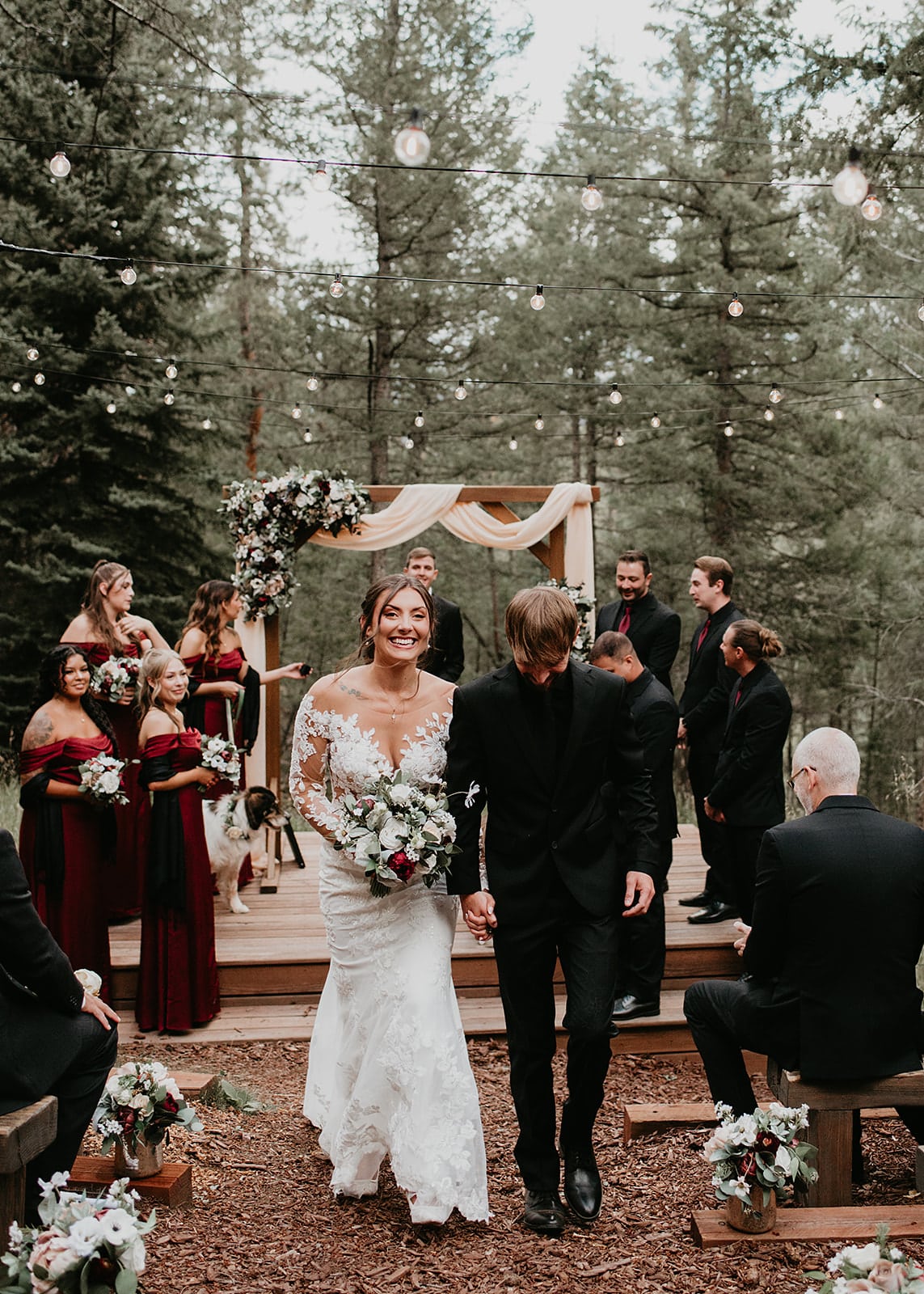 Ceremony in the meadow with string quartet and burgundy floral arch.