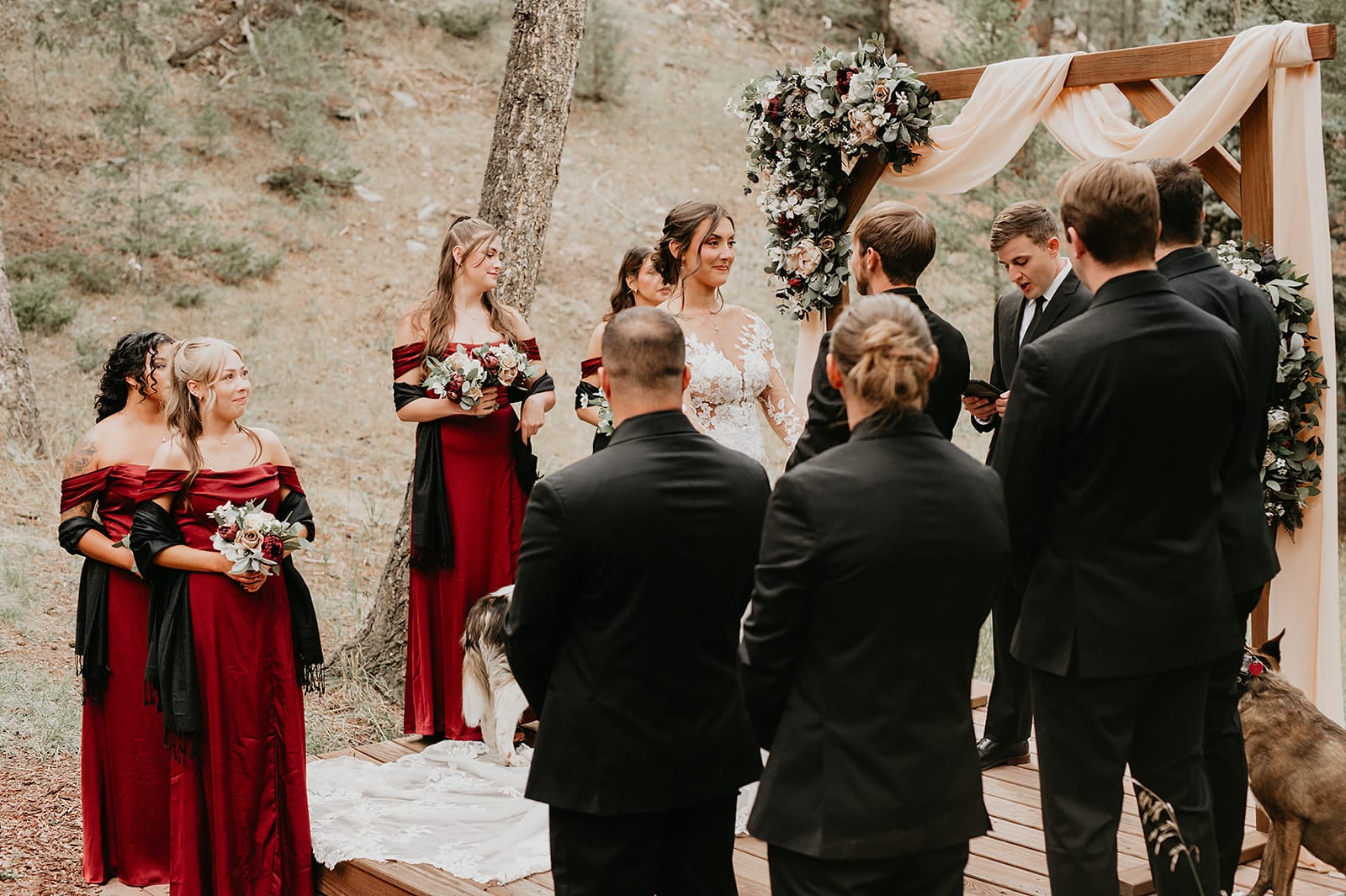 Ceremony in the meadow with string quartet and burgundy floral arch.