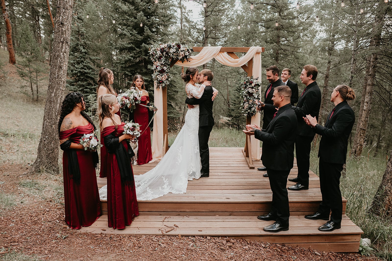 Ceremony in the meadow with string quartet and burgundy floral arch.