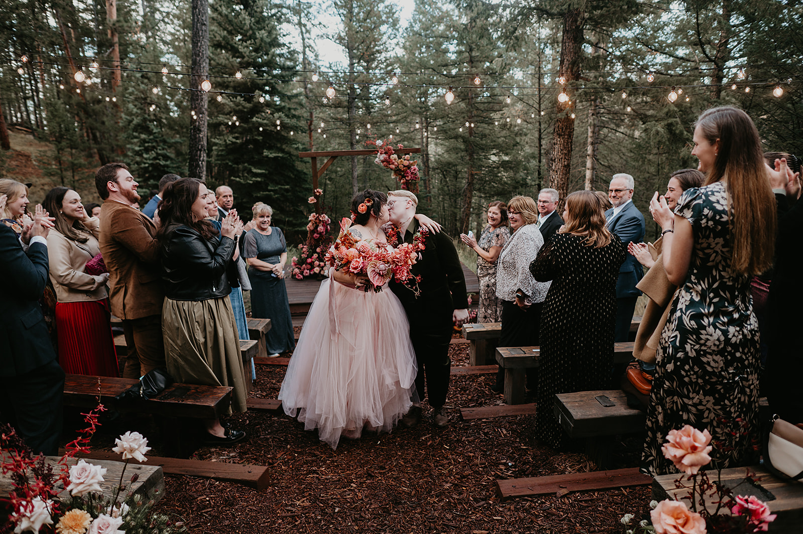 Sarah and Kellie seal their vows with a kiss during their Evergreen Colorado fall wedding ceremony at Juniper Lodge & Treehouses.
