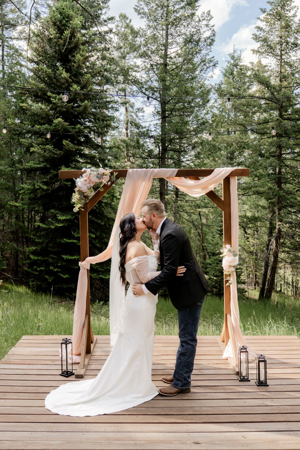 The couple shares their first kiss surrounded by family during their Evergreen Colorado wedding at Juniper Lodge & Treehouses.