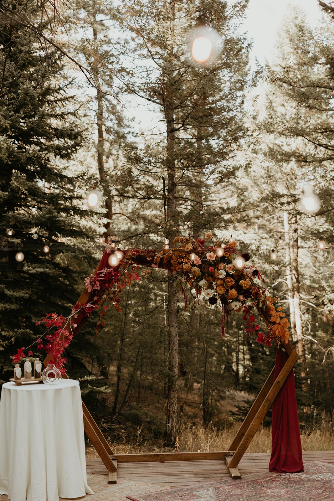 Meadow ceremony with hexagon arch, fall florals, and rust drapery at Juniper Lodge & Treehouses.
