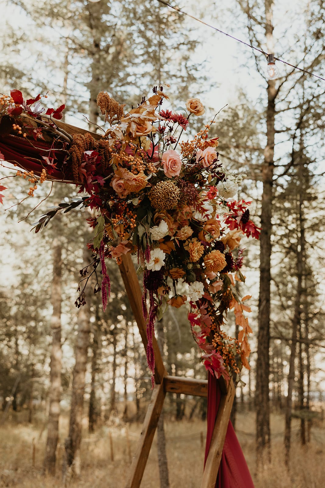 Meadow ceremony with hexagon arch, fall florals, and rust drapery at Juniper Lodge & Treehouses.
