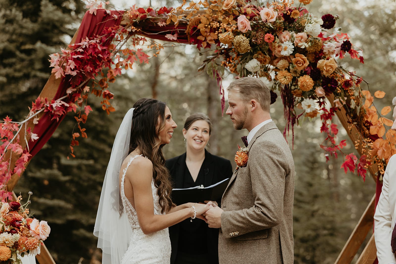 Meadow ceremony with hexagon arch, fall florals, and rust drapery at Juniper Lodge & Treehouses.